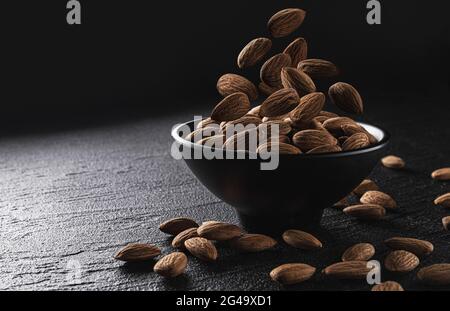 Falling almond nuts on black background with copy space Stock Photo