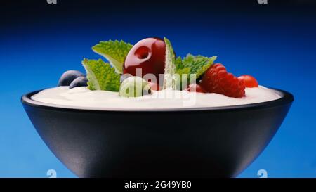 Bowl of yogurt with wild berries: strawberry, blueberry, raspberry Stock Photo