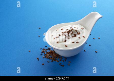 Yogurt with flax seeds isolated on blue background Stock Photo