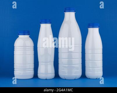 Plastic milk bottles isolated on blue background Stock Photo