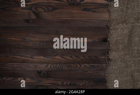Old burlap fabric napkin on brown wooden background, top view Stock Photo