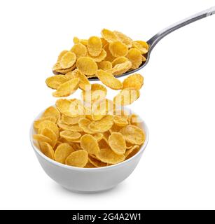 Corn flakes falling from spoon into bowl isolated on white background Stock Photo