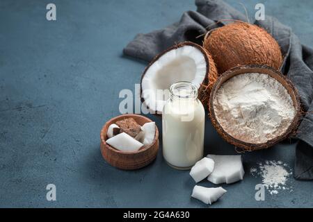 Coconut milk, flour and coconuts on a blue background. Side view, copy space. Stock Photo