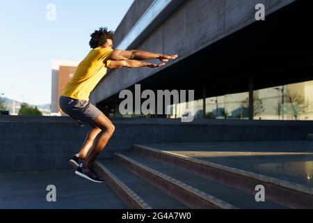 Black man doing squats with jumping on a step. Stock Photo