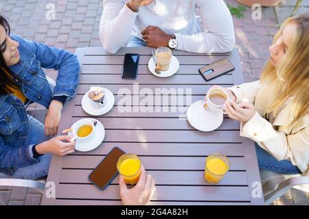 Top view of people drinking coffee, juice and tea sitting at the table on the terrace of a bar. Stock Photo