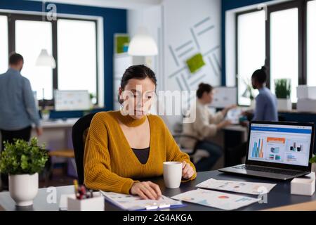 Manager of financial company reading analysing statistics and team working on deadline. Executive entrepreneur, manager leader sitting working on projects with diverse teamworkers. Stock Photo
