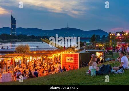 Wien, Vienna: recreational area Copa Beach at river Neue Donau (New Danube), people on meadow, bar, view to Wienerwald and Millennium Tower in 22. Don Stock Photo