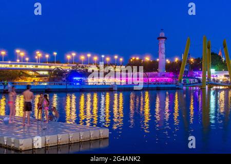 Wien, Vienna: recreational area Copa Beach at river Neue Donau (New Danube), view to Sunken City area at island Donauinsel, floating bridge, people on Stock Photo
