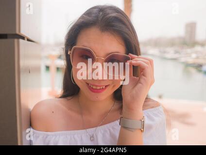 high key portrait of young beautiful and attractive Asian Japanese woman wearing cool sunglasses posing outdoors on a sunny day in beauty and fashion Stock Photo