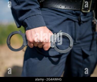 Police officer holding handcuffs Stock Photo - Alamy