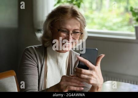 Smiling mature woman have video call on cellphone Stock Photo