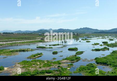 View of a low-flowing river and adjacent fields in countryside to the south of Shenyang in Liaoning province, China. Stock Photo