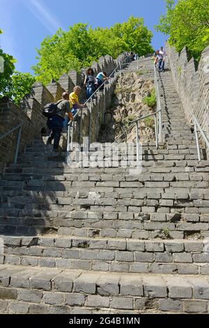 Visitors climb the steep steps of the great wall at Hushan on the border with North Korea. Dandong, China. Stock Photo