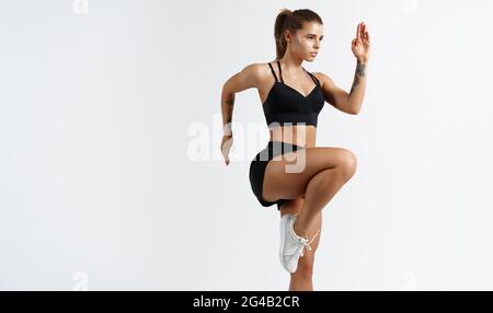 Female runner doing fitness workout. Slim woman athlete exercising on white background Stock Photo
