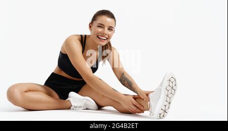 Athletic girl stretch legs and look at camera Stock Photo by