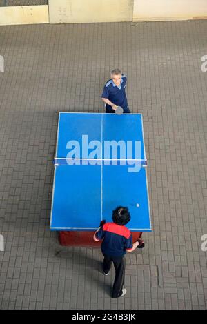A couple play table tennis at a local sports venue under a flyover in Shenyang, China Stock Photo