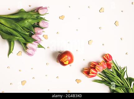 Spring beautiful tulip flowers on soft light background with wooden hearts and red apple with inscription I love you. Mother's day, greeting card fest Stock Photo