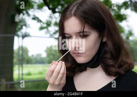 London, UK. 20th June, 2021. An 18 year old performs a PCR test at an outdoor mobile testing centre on Clapham Common. Surge testing has started in Lambeth in response to local rises in cases of the delta variant, part of a possible third wave or coronavirus in England. Credit: Anna Watson/Alamy Live News