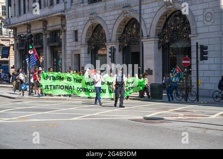 Small group of protest marchers, escorted by a police officer, pass by the Ritz Hotel, Piccadilly, London, Engand, UK Stock Photo