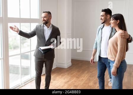 Estate Agent In Suit Showing Buyers New Empty Apartment Stock Photo
