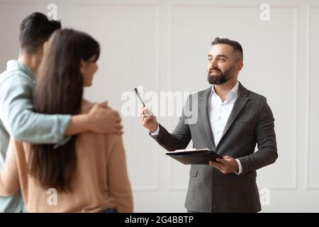 Couple Buying New Apartment Talking With House Agent Stock Photo