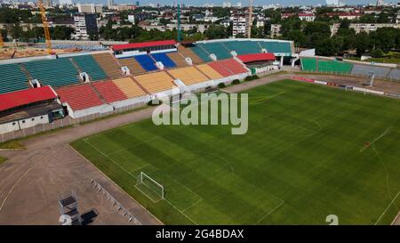 Football stadium in the city park. A green field and stands are visible, painted in different colors. Close-up shot. Aerial photography. Stock Photo