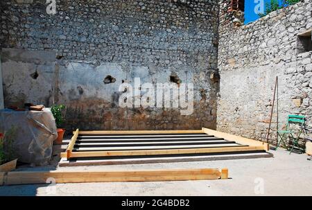 A concrete base for building a small prefabricated wooden cabin on. The cabin's wooden foundation beams have been placed on top of the concrete base. Stock Photo