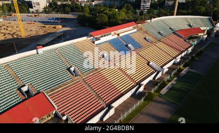 Football stadium in the city park. A green field and stands are visible, painted in different colors. Close-up shot. Aerial photography. Stock Photo