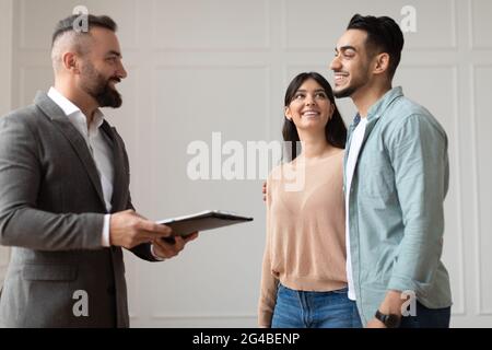 Couple Buying New Apartment Talking With House Agent Stock Photo