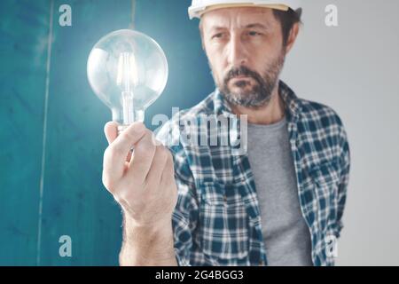 Construction engineer holding light bulb as symbol of creativity and new ideas, selective focus Stock Photo