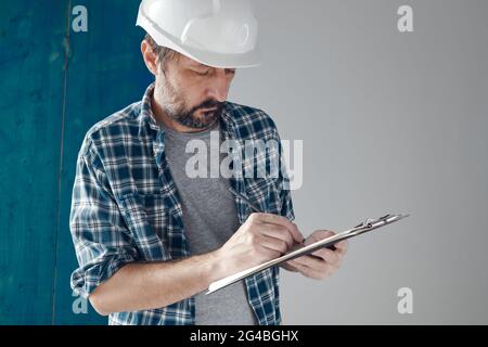 Construction engineer writing project notes on clipboard notepad paper, selective focus Stock Photo