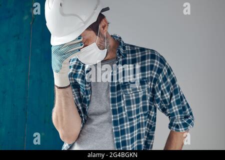 Worried construction engineer with protective face mask, conceptual image for covid-19 pandemic Stock Photo