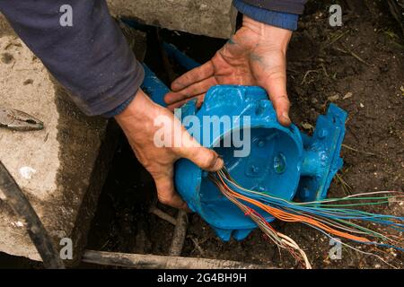 The hands of an electrician are assembling a box of electrical equipment. Maintenance work for outdoor lighting in the park. Stock Photo