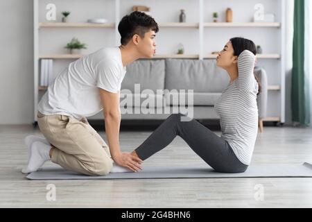 Motivated asian man and woman working on abs at home Stock Photo