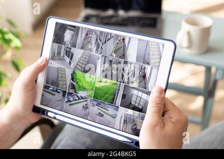 Man monitoring modern cctv cameras on digital tablet indoors Stock Photo