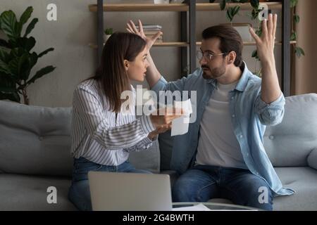 Stressed emotional young family couple arguing, paying bills. Stock Photo