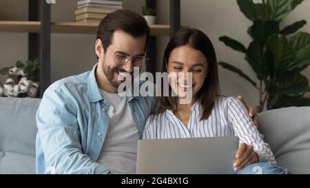 Laughing happy young couple using computer at home. Stock Photo