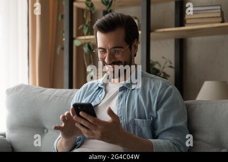 Happy young man in eyeglasses using smartphone. Stock Photo