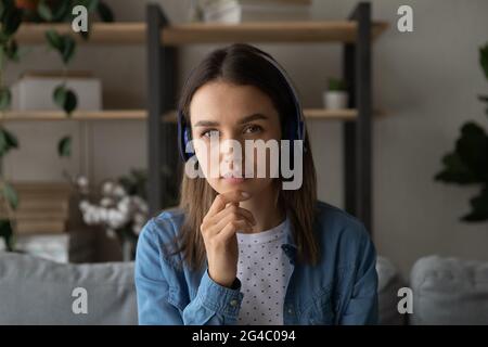 Thoughtful young woman in headphones looking at camera. Stock Photo