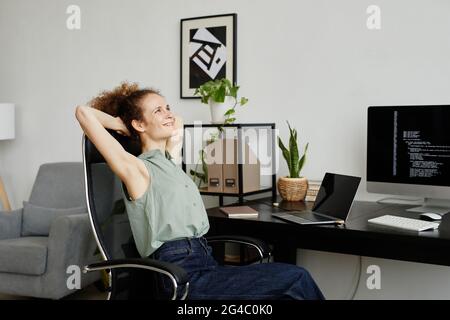 Young programmer sitting on comfortable chair and stretching she resting after hard with computers Stock Photo