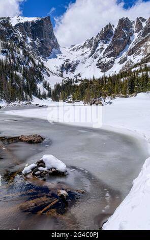 Spring Mountain Lake - A wide-angle vertical view of Hallett Peak and Flattop Mountain towering at shore of still-mostly-frozen Dream Lake. RMNP, CO. Stock Photo