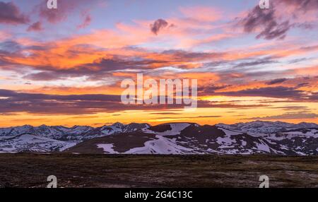 Spring Mountain Sunset - A panoramic view of colorful Spring sunset sky over snow-capped high peaks of the Continental Divide at top of RMNP, CO, USA.