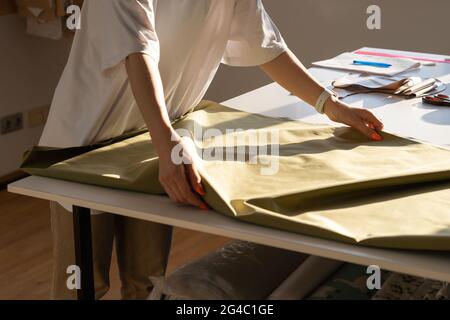Closeup of female sewer hold fabric to cut working in workshop studio. Creative process in atelier Stock Photo