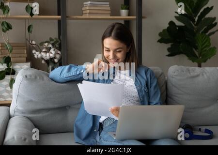 Smiling young freelance woman working with documents at home. Stock Photo