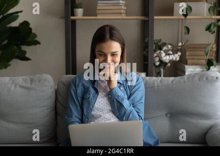 Happy young woman using computer at home. Stock Photo
