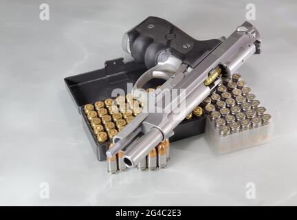 Beretta 92FS or M9 hand gun open slide and pack of bullets 9mm parabellum isolated on reflection surface. Stock Photo