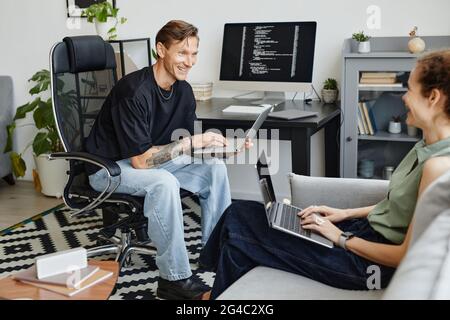 Two business colleagues working on computers and discussing computer software together in the room Stock Photo