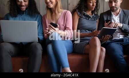 Cropped image young friendly multiracial people using different gadgets. Stock Photo