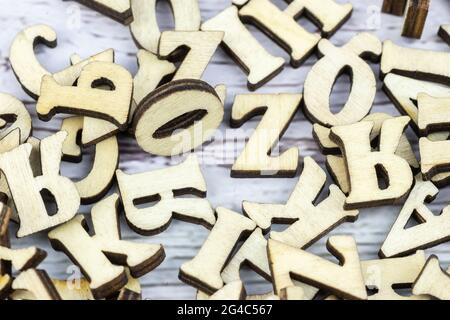A stack of small wooden letters on a dark table. Letters outlines for arranging inscriptions and words. Dark background. Stock Photo
