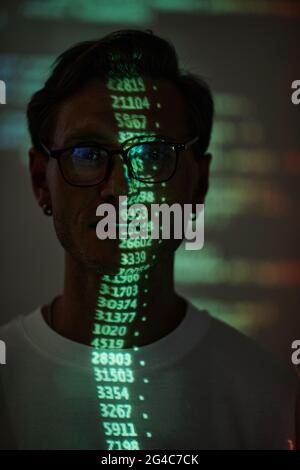 Hacker working on personal computer projecting code numbers and characters reflect on his face Stock Photo